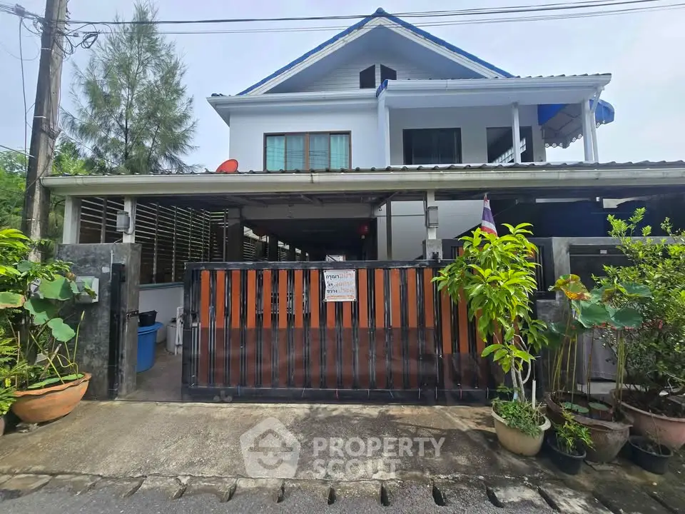 Charming two-story house with gated entrance and lush greenery, perfect for family living.