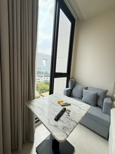 Modern living room with marble table and cozy sofa, featuring large windows with city view.