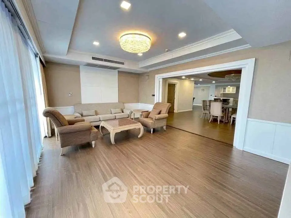 Spacious living room with elegant chandelier and open layout to dining area.