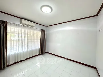 Spacious empty room with large window and air conditioning, perfect for customization.