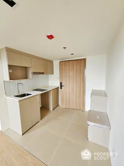 Modern compact kitchen with sleek cabinetry and integrated appliances in a minimalist apartment.