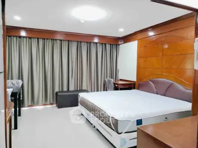 Spacious bedroom with modern furnishings and large window for natural light.