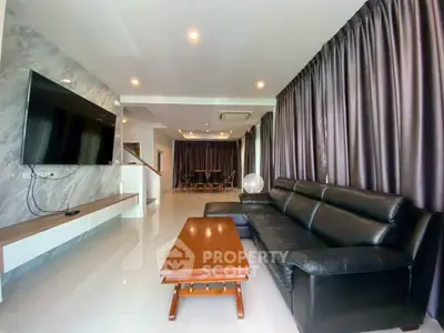 Spacious modern living room with sleek leather sofa and large TV, perfect for relaxation.