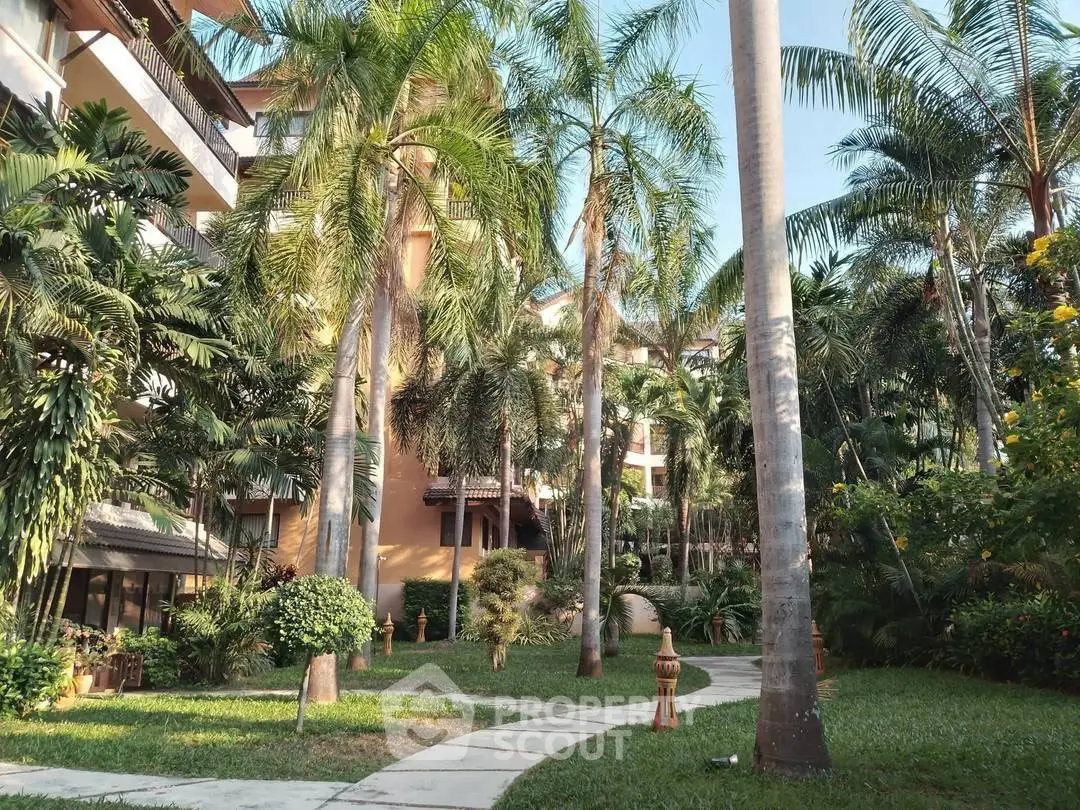 Lush tropical garden with palm trees and pathway in a residential complex