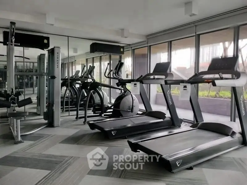 Modern gym with state-of-the-art equipment and large windows for natural light.