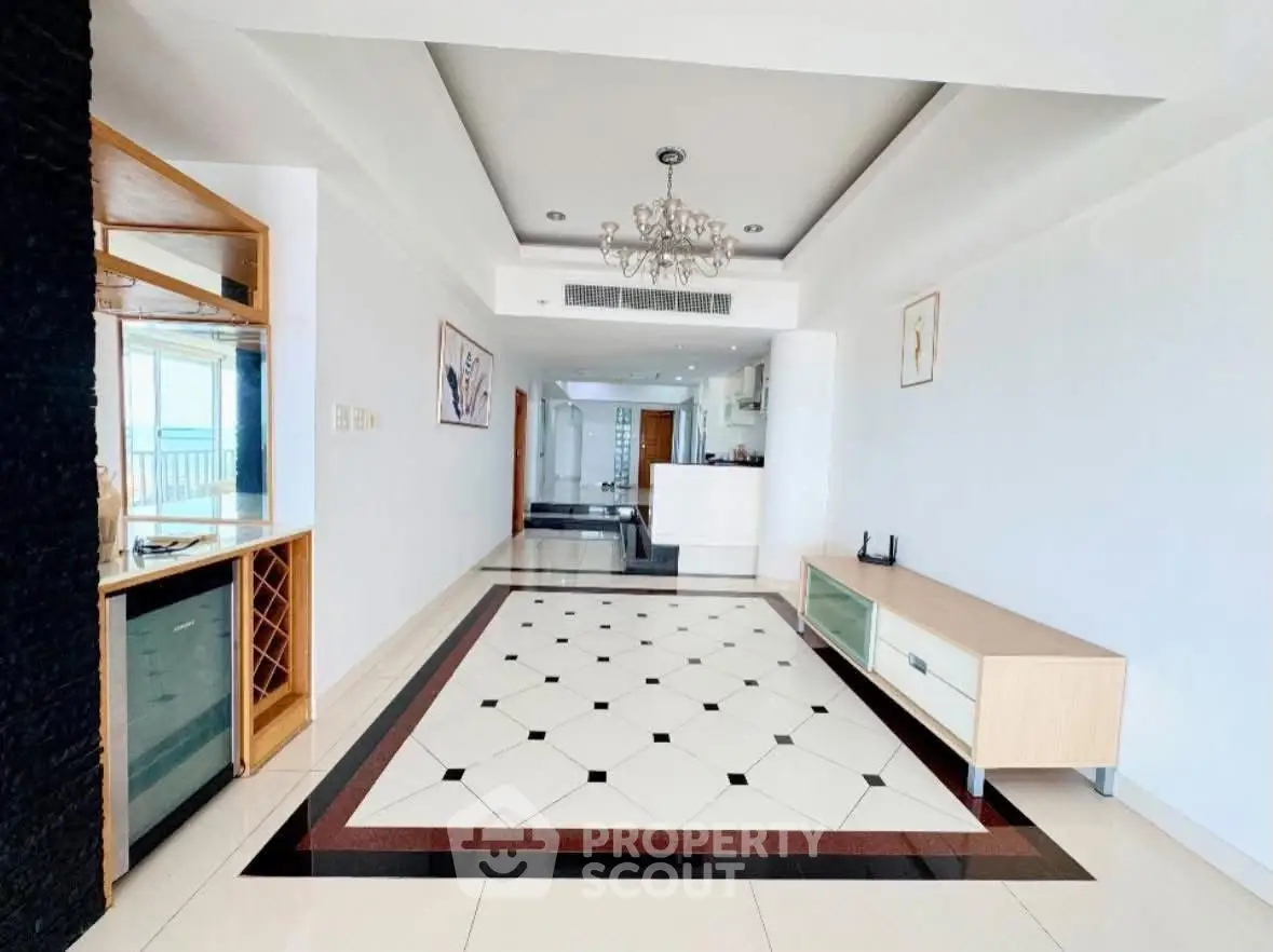 Spacious modern living room with elegant chandelier and stylish flooring in a luxury apartment.