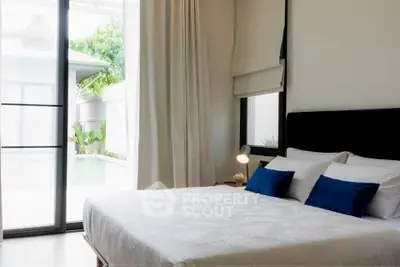 Luxurious bedroom with pool view and elegant decor, featuring large windows and plush bedding.