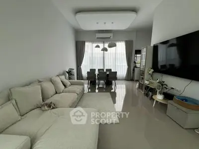 Spacious modern living room with large sofa and dining area, featuring sleek design and ample natural light.