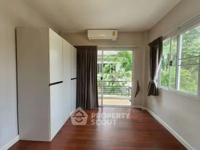 Spacious bedroom with wooden flooring and balcony access in modern home