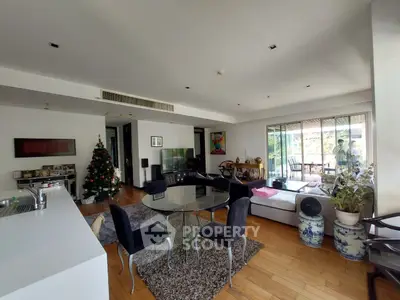 Spacious living room with modern decor and Christmas tree, featuring open layout and balcony access.