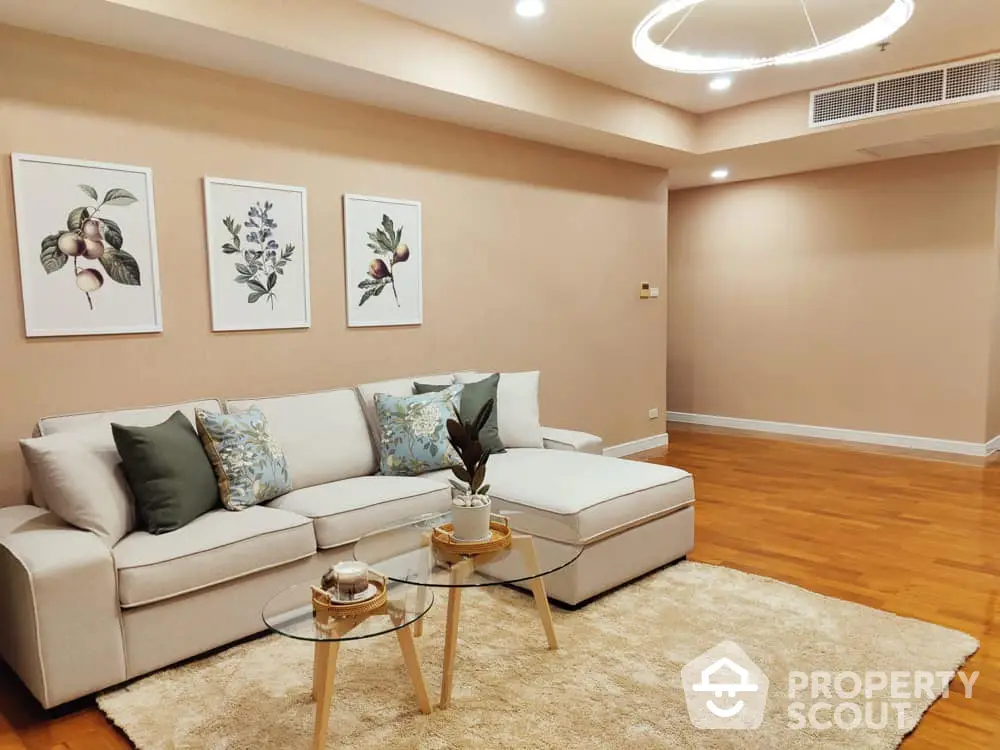 Spacious living room with polished hardwood floors, modern L-shaped sofa, elegant wall art, and recessed lighting, ideal for comfortable urban living.