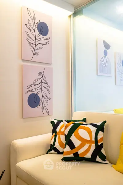 Stylish living room with modern art and colorful cushions on a white sofa, perfect for contemporary living.