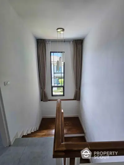 Elegant staircase with wooden railing and natural light from window