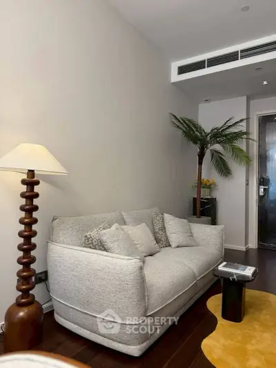 Stylish living room with modern sofa, elegant lamp, and indoor palm tree, perfect for relaxation.