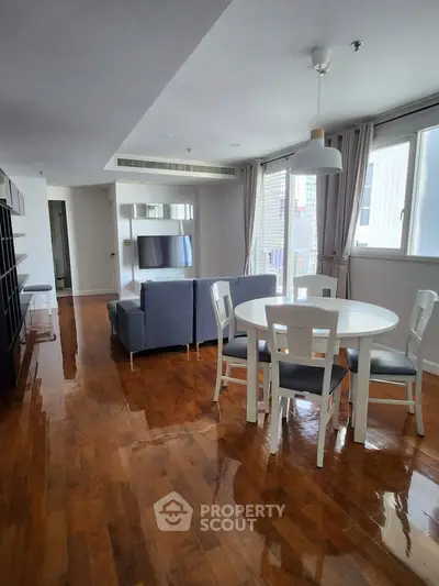 Spacious living room with modern furniture and polished wooden floors in a bright apartment.