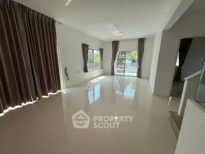 Spacious living room with large windows and glossy floor tiles, perfect for natural light lovers.