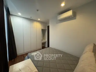 Modern bedroom with built-in wardrobe and air conditioning in a stylish apartment.
