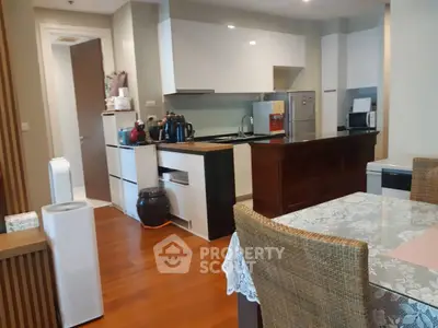 Modern kitchen with open layout and dining area, featuring sleek appliances and wooden flooring.