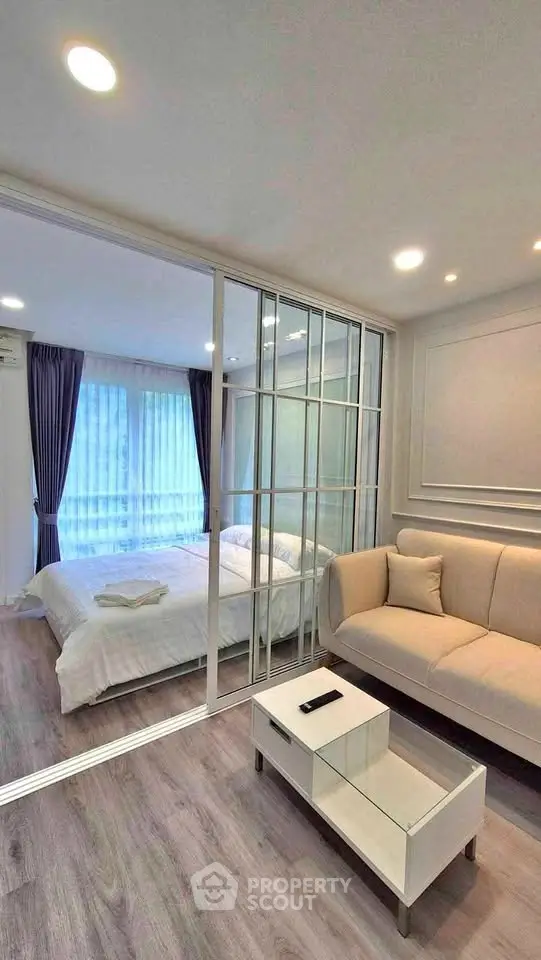 Modern studio apartment with glass partition, cozy living area, and elegant bedroom.