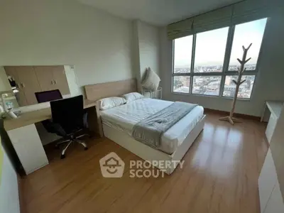 Spacious bedroom with large window offering stunning city views, modern furnishings, and ample natural light.
