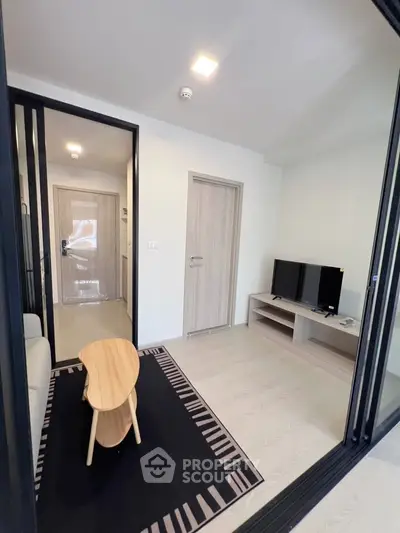 Modern living room with sleek furniture and TV, featuring a stylish wooden coffee table and elegant decor.