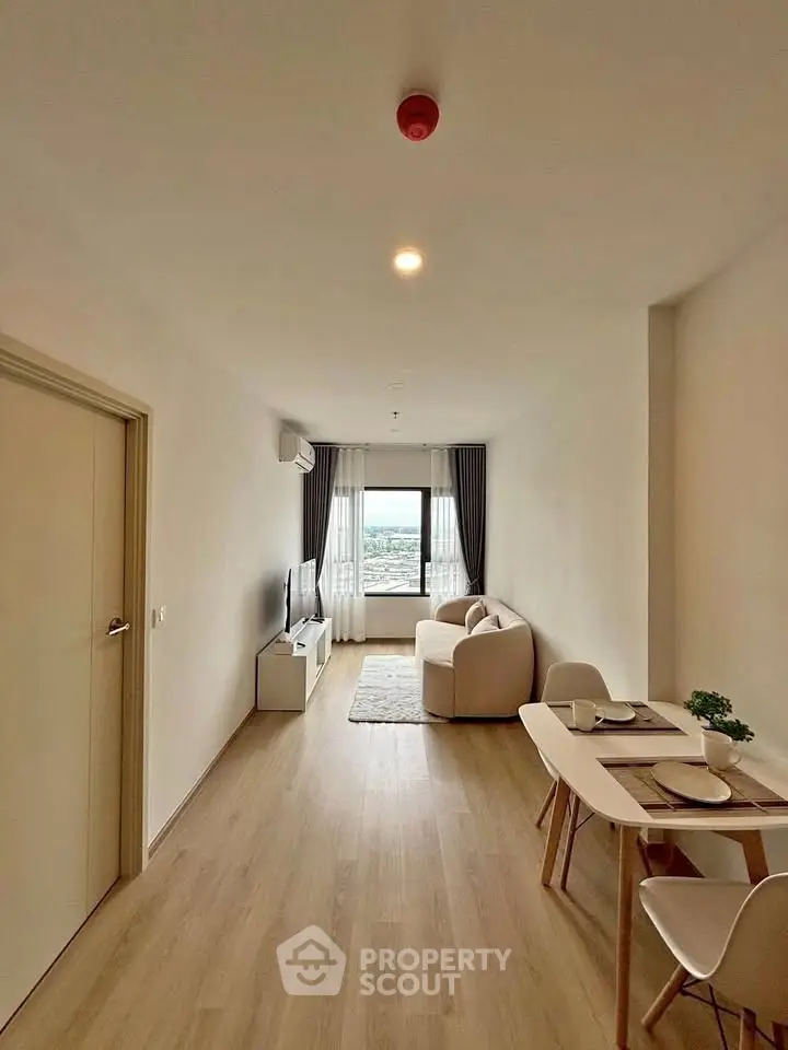 Modern living room with cozy seating and dining area, featuring a large window with a scenic view.