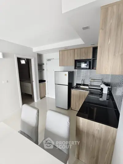 Modern kitchen with sleek wooden cabinets and stainless steel appliances in a stylish apartment.