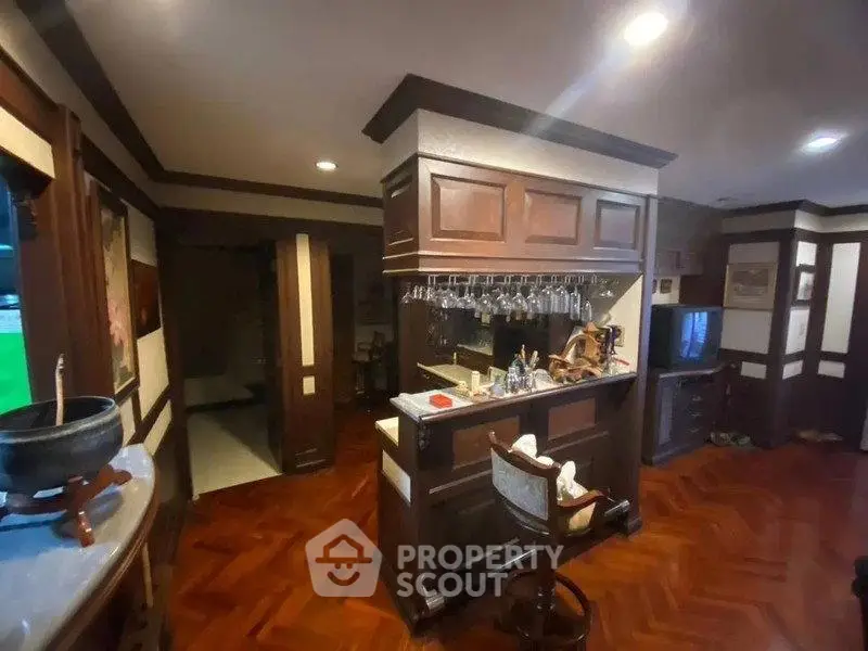 Elegant home bar with wooden cabinetry and parquet flooring