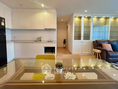 Modern open-plan living room and kitchen with stylish decor and glass dining table.