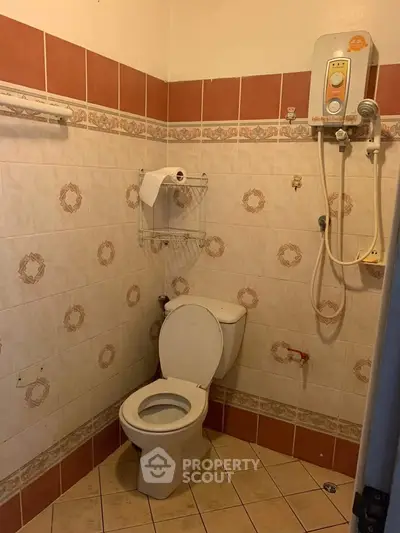 Compact bathroom with tiled walls, toilet, and wall-mounted water heater.