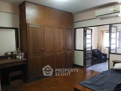 Spacious bedroom with wooden wardrobe and parquet flooring in cozy apartment