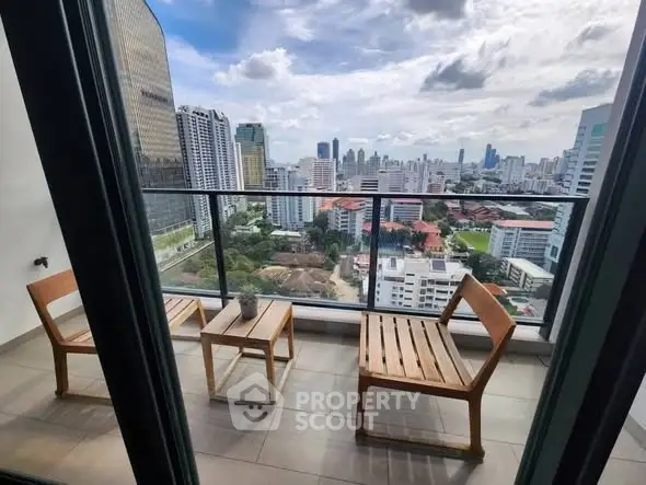 Stunning city view from a high-rise balcony with modern seating.