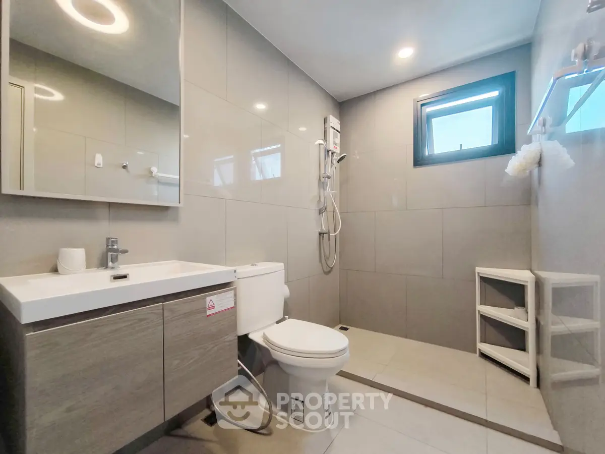 Modern bathroom with sleek fixtures and natural light, featuring a shower and vanity.