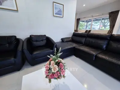 Spacious living room with black leather sofas and elegant floral centerpiece