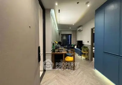 Modern living room with stylish decor and open layout, featuring blue cabinetry and wooden dining table.