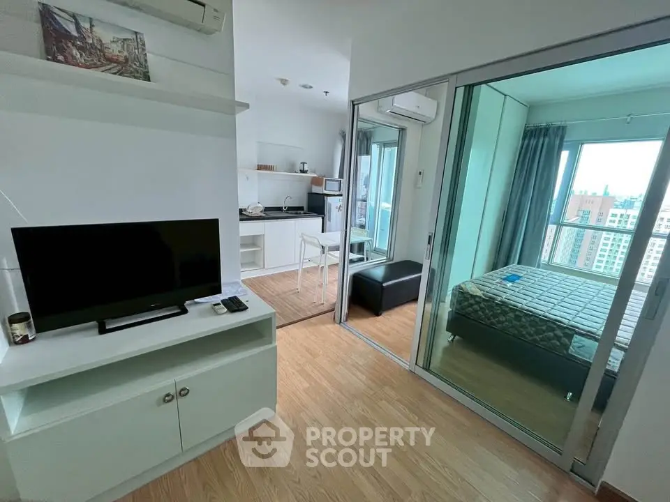 Modern apartment interior with open layout, featuring a cozy living area, compact kitchen, and a bedroom with city view.