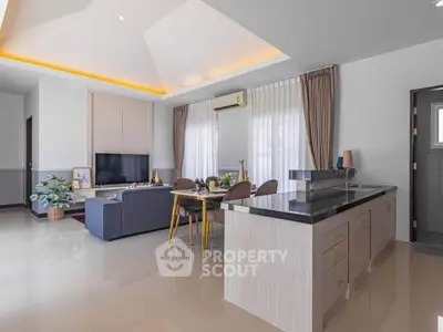 Spacious modern living room with open kitchen, elegant decor, and natural light.