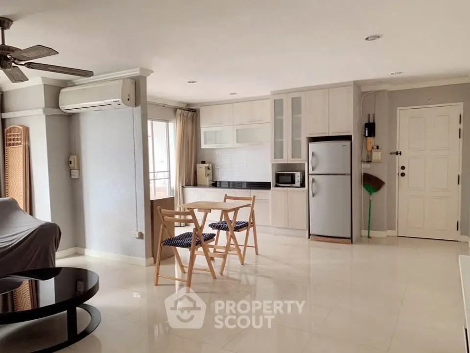 Spacious open-plan living room with modern kitchen and dining area, featuring sleek appliances and ample natural light.