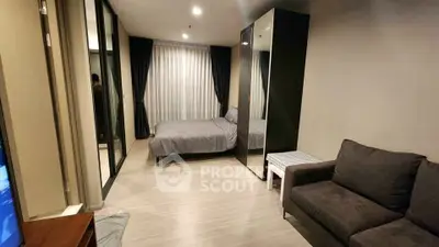 Modern bedroom with mirrored wardrobe and cozy seating area in stylish apartment.