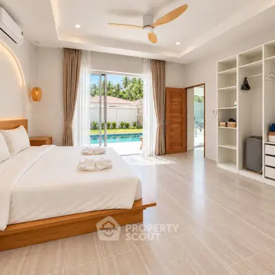 Luxurious bedroom with pool view, modern decor, and ample natural light in a tropical setting.
