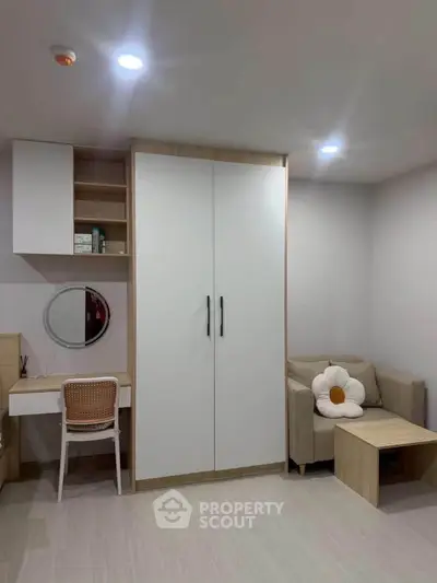 Cozy bedroom with modern wardrobe, desk, and comfortable seating area.