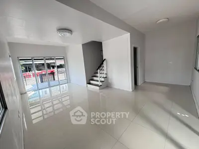 Spacious modern living room with sleek tile flooring and staircase, perfect for contemporary living.