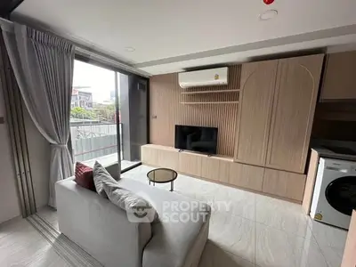 Modern living room with balcony, stylish furniture, and washing machine in sleek apartment.