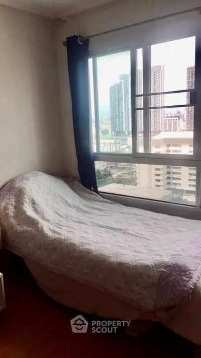 Cozy bedroom with city view, featuring a single bed and large window for natural light.