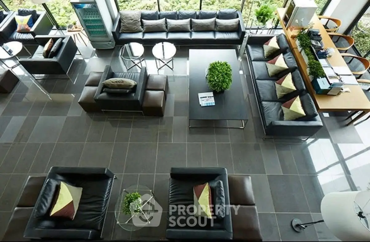 Luxurious modern living room with sleek black leather sofas and large windows offering natural light.