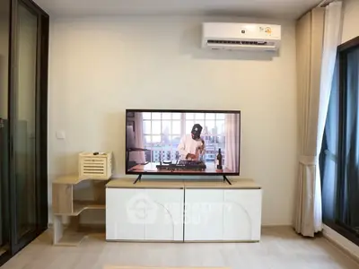 Modern living room with air conditioning and entertainment center featuring a large TV.
