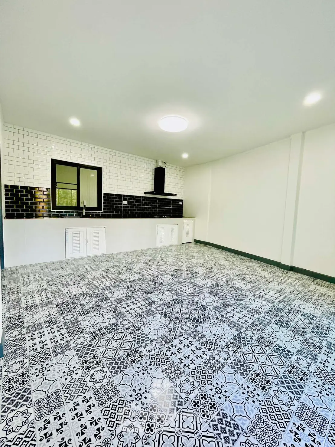 Spacious kitchen with stylish patterned flooring and modern black and white design.