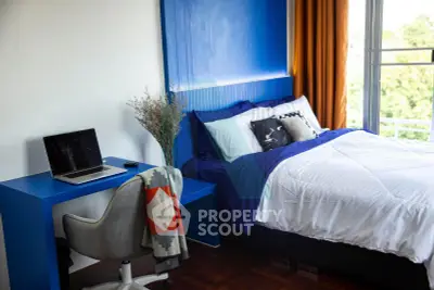 Modern bedroom with blue accents and balcony view, featuring a cozy workspace.