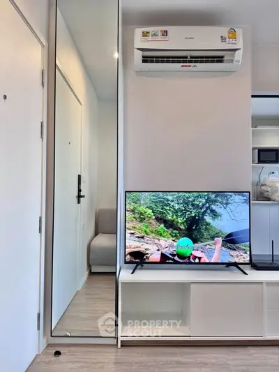 Modern living room with sleek design, featuring a wall-mounted air conditioner and flat-screen TV.