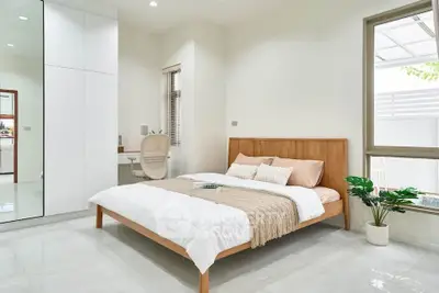 Modern minimalist bedroom with wooden bed frame and large window, perfect for serene living.